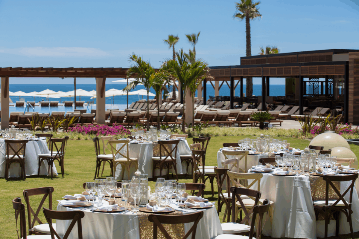 Banquete de boda en jardín de Krystal Grand Los Cabos con mesas decoradas, vista al mar y ambiente elegante.
